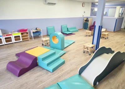 Photo de la salle de vie de la micro crèche de Juvisy-sur-Orge avec des modules en mousse, une petite cuisine et un toboggan pour enfant